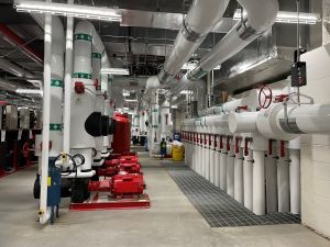 White pipes and ductwork are seen in a basement mechanical room