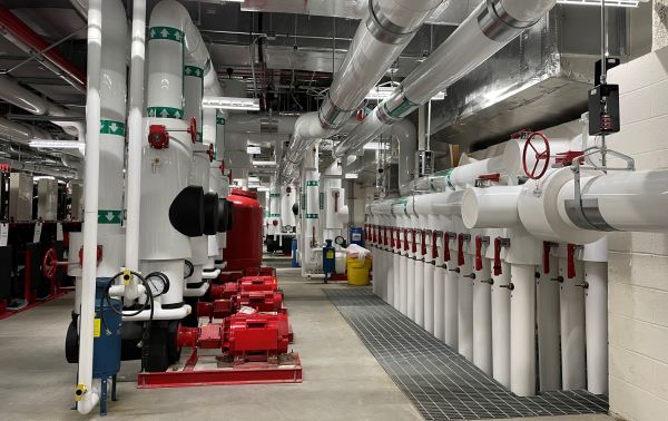 ETEC's mechanical room, showing large white pipes rising vertically from the floor and running horizontally along the ceiling.