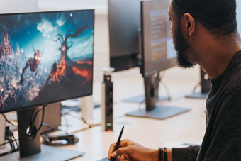 A game developer works on a new game’s visual design at his desk.