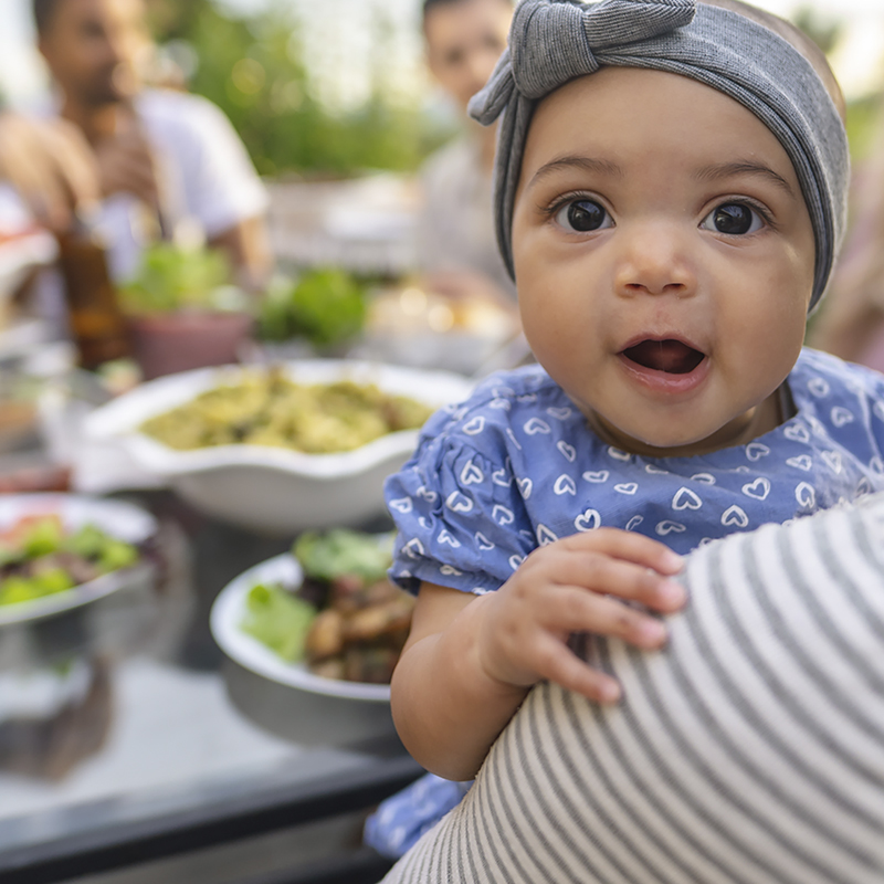 Baby being held near table full of food