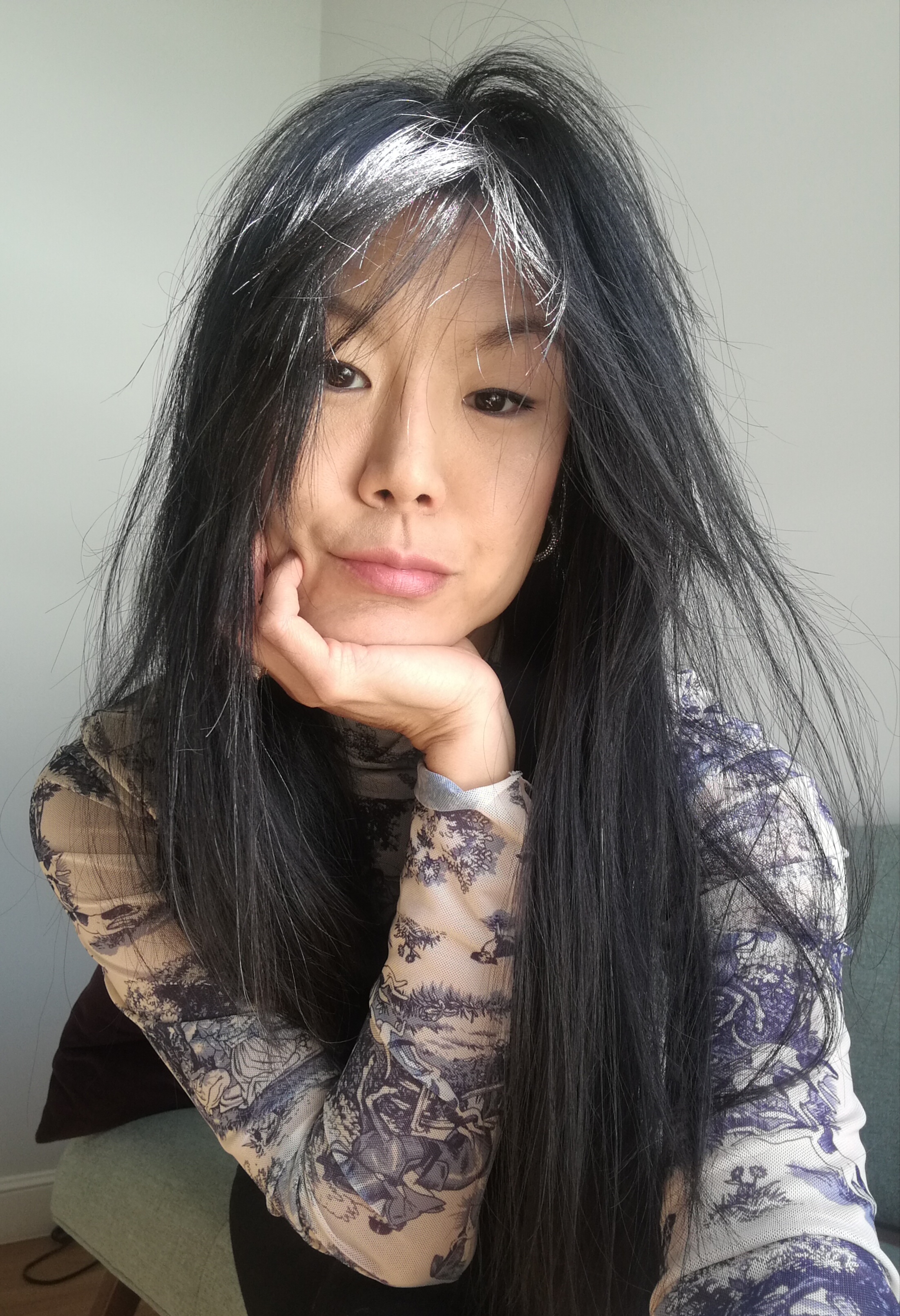 woman with long black hair stairs ahead with chin in hand