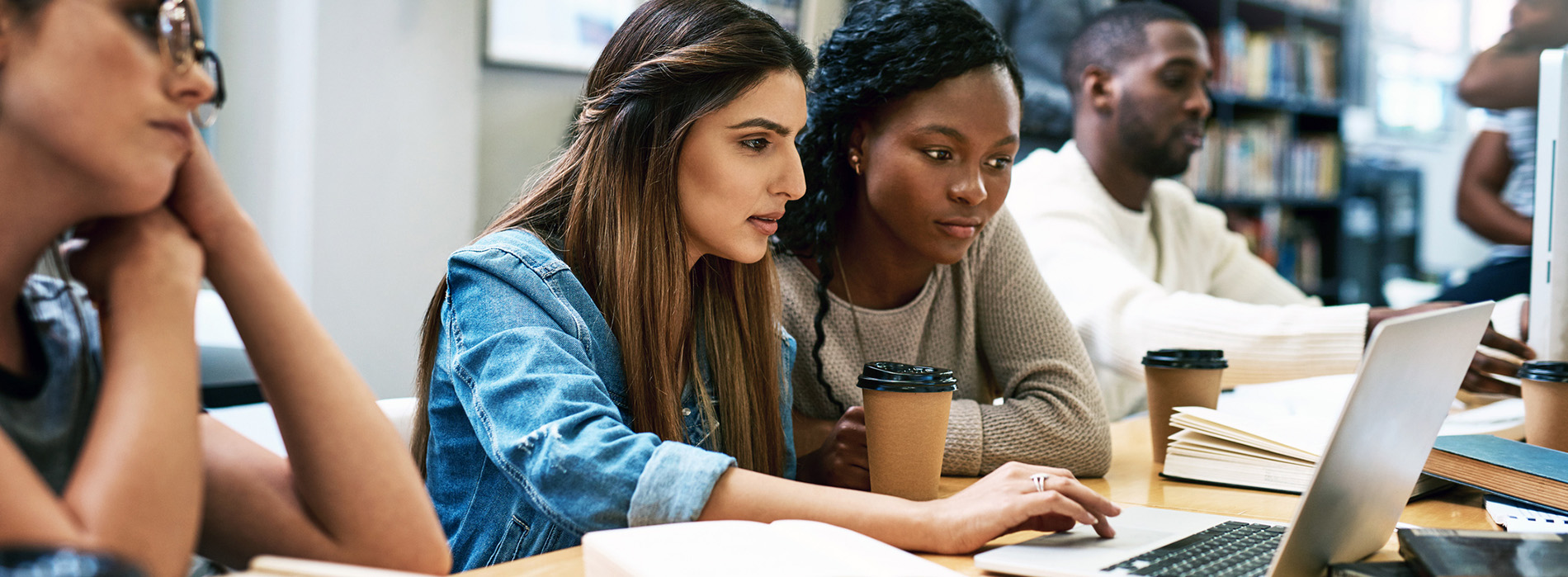 Female students in the UAlbany Downtown Library working on a laptop computer..
