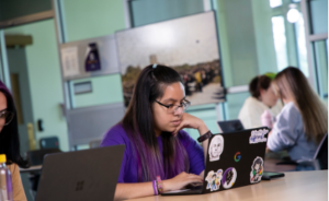 A student works on a laptop inside a shared study space.