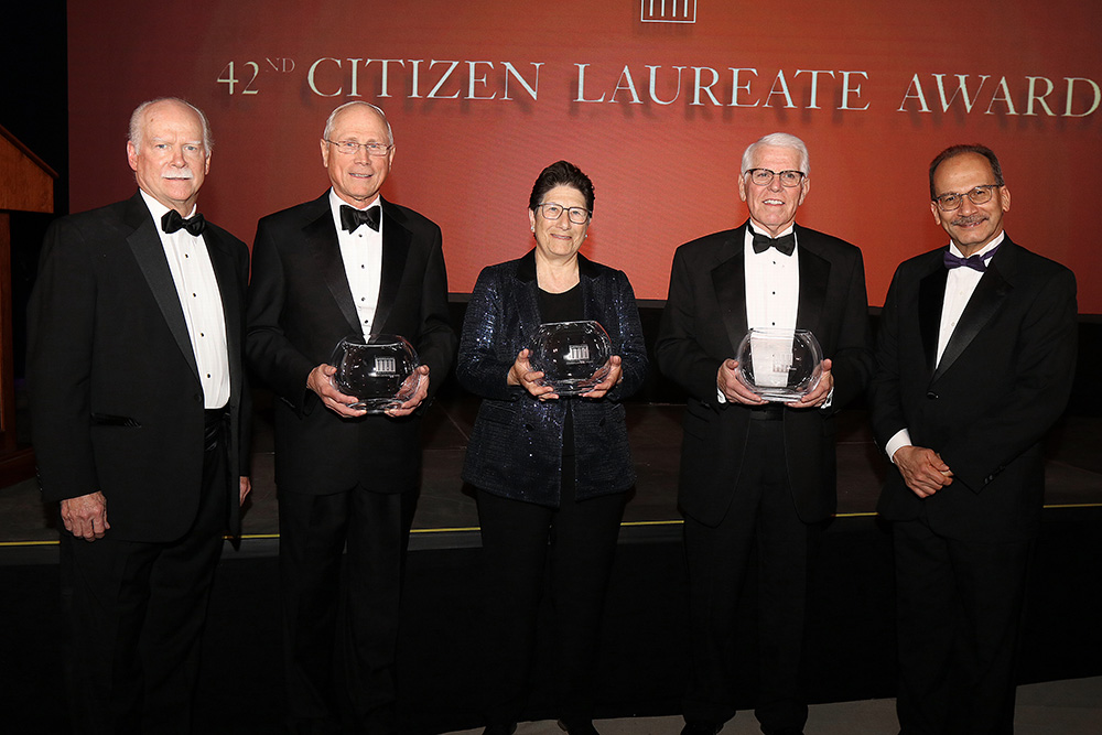 2023 Citizen Laureates hold awards while standing next to George Hearst and President Rodriguez in front of wall with the Citizen Laureate Awards logo.