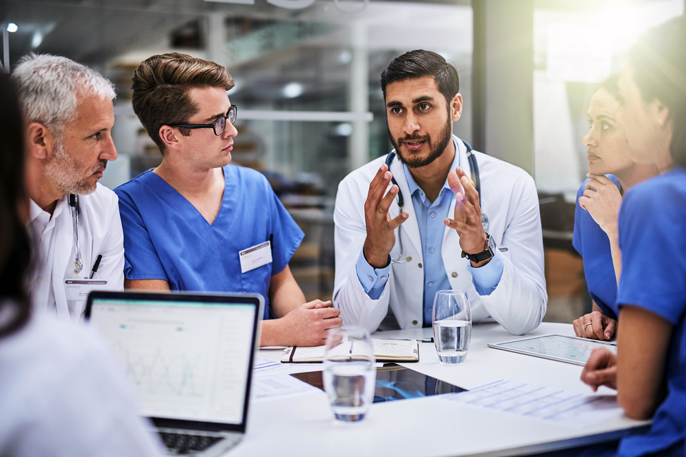 A group of medical professionals having a discussion around a conference table.