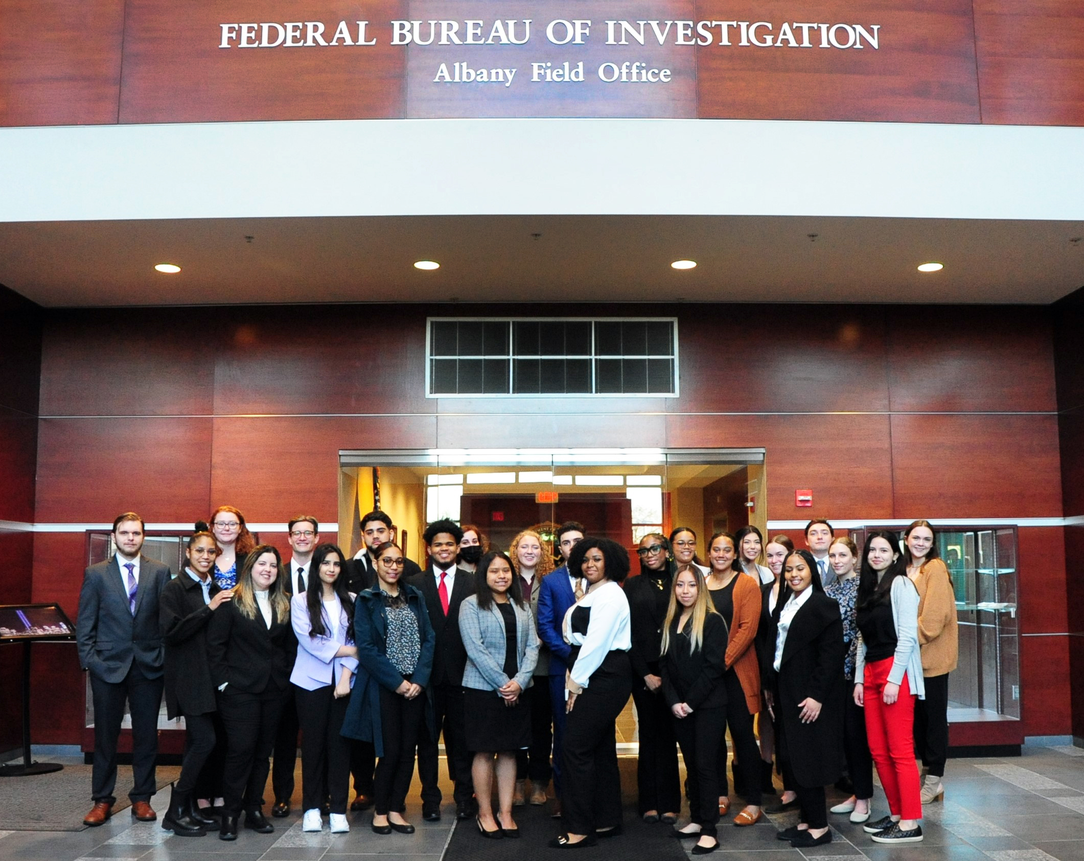 A large group of UAlbany students standing inside the Federal Bureau of Investigation Albany Field Office building.