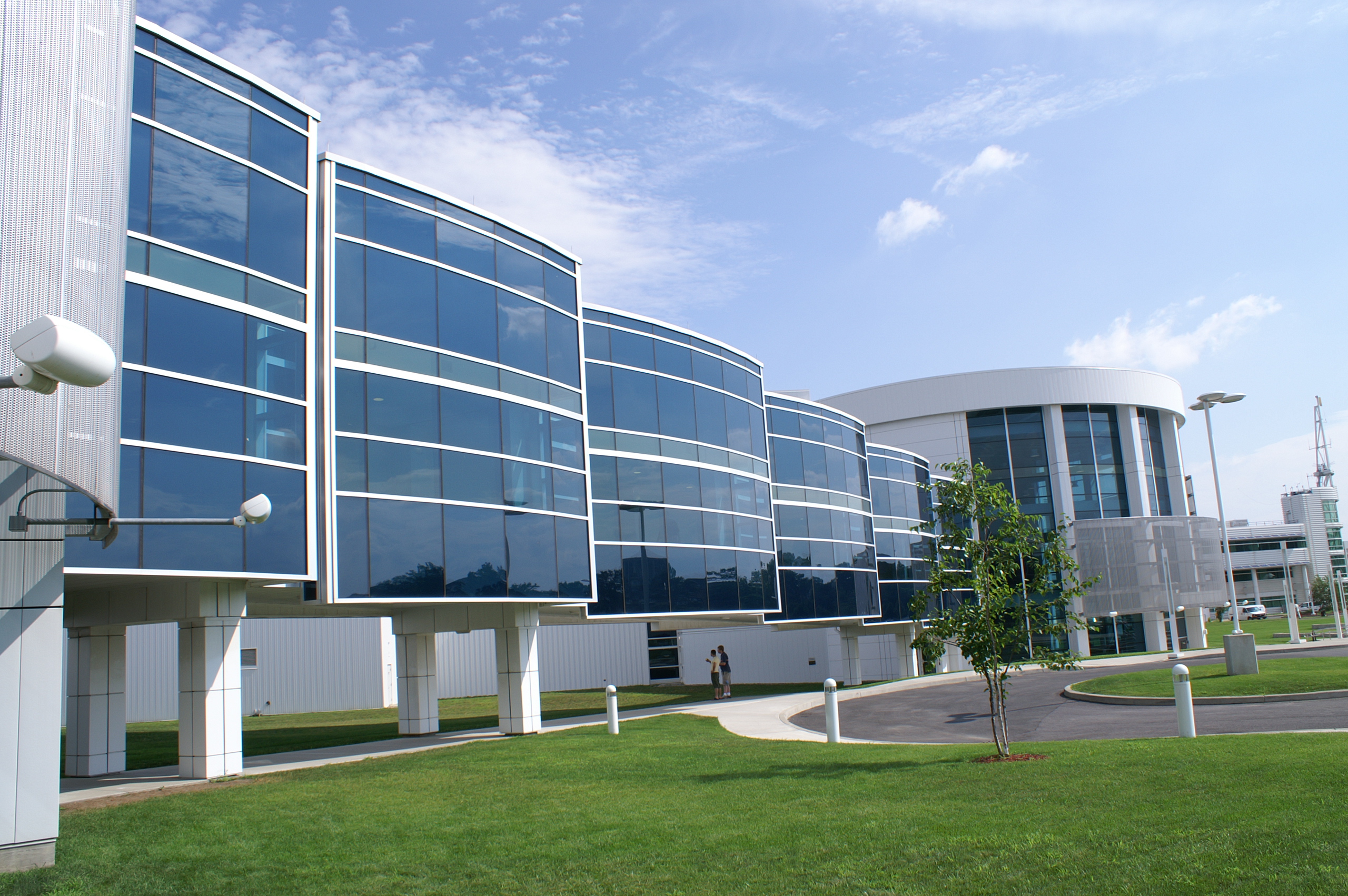 The CNSE campus, with multiple glass and steel buildings situated next to lush green lawn and a curved roadway.