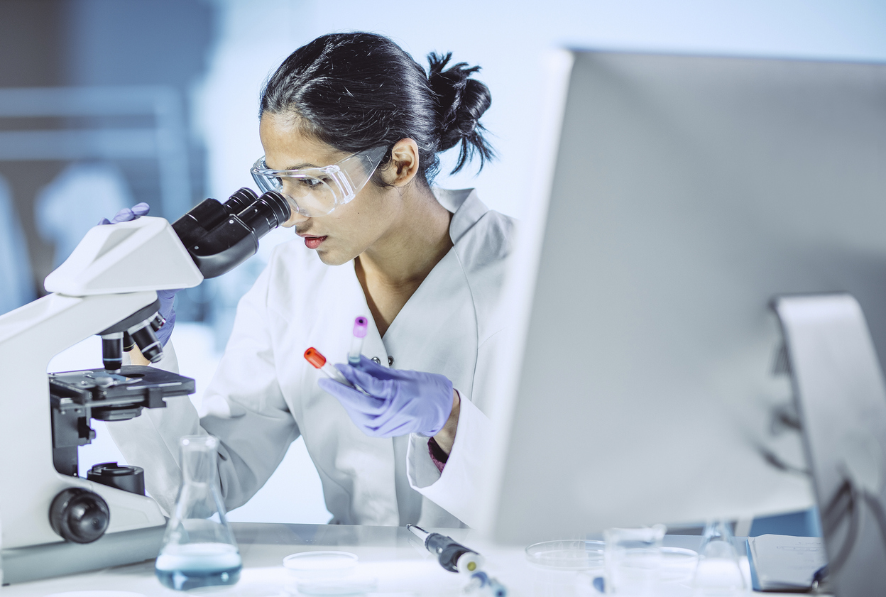 Female scientist looking into a microscope in a lab
