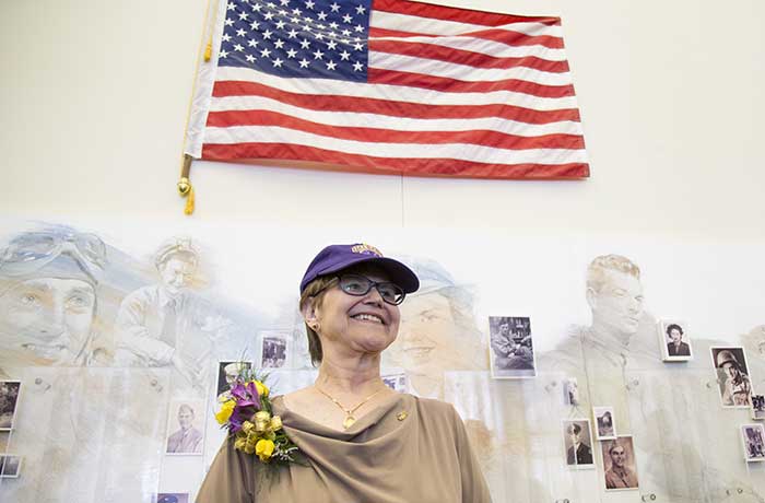 Polly Weidenkopf stands in front of UAlbany alumni veteran wall and American flag