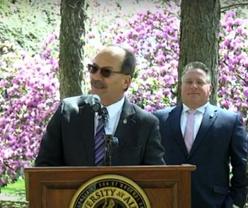 President Rodriguez speaks at a podium in front of spring blossoms