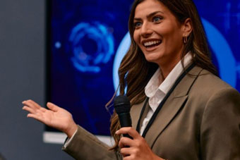 A public relations specialist answers questions at a press conference.