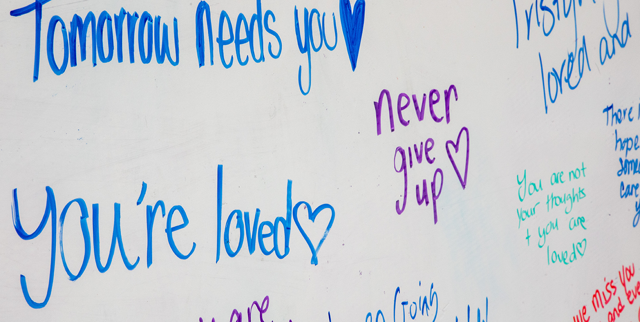 Encouraging messages are written on a whiteboard during UAlbany's annual Out of the Darkness Walk. Messages read "tomorrow needs you," "you're loved," "never give up" and "you are not your thoughts and you are loved."