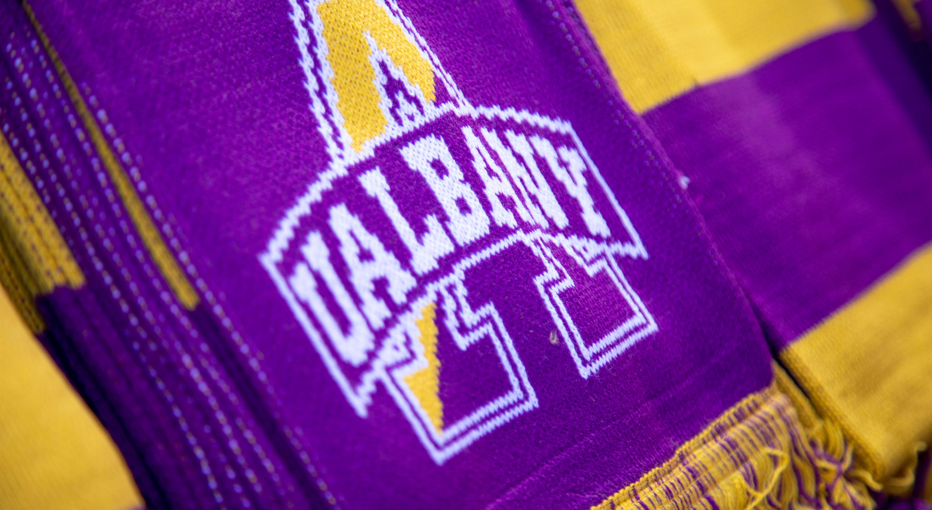 The UAlbany logo on a purple and gold knit scarf.