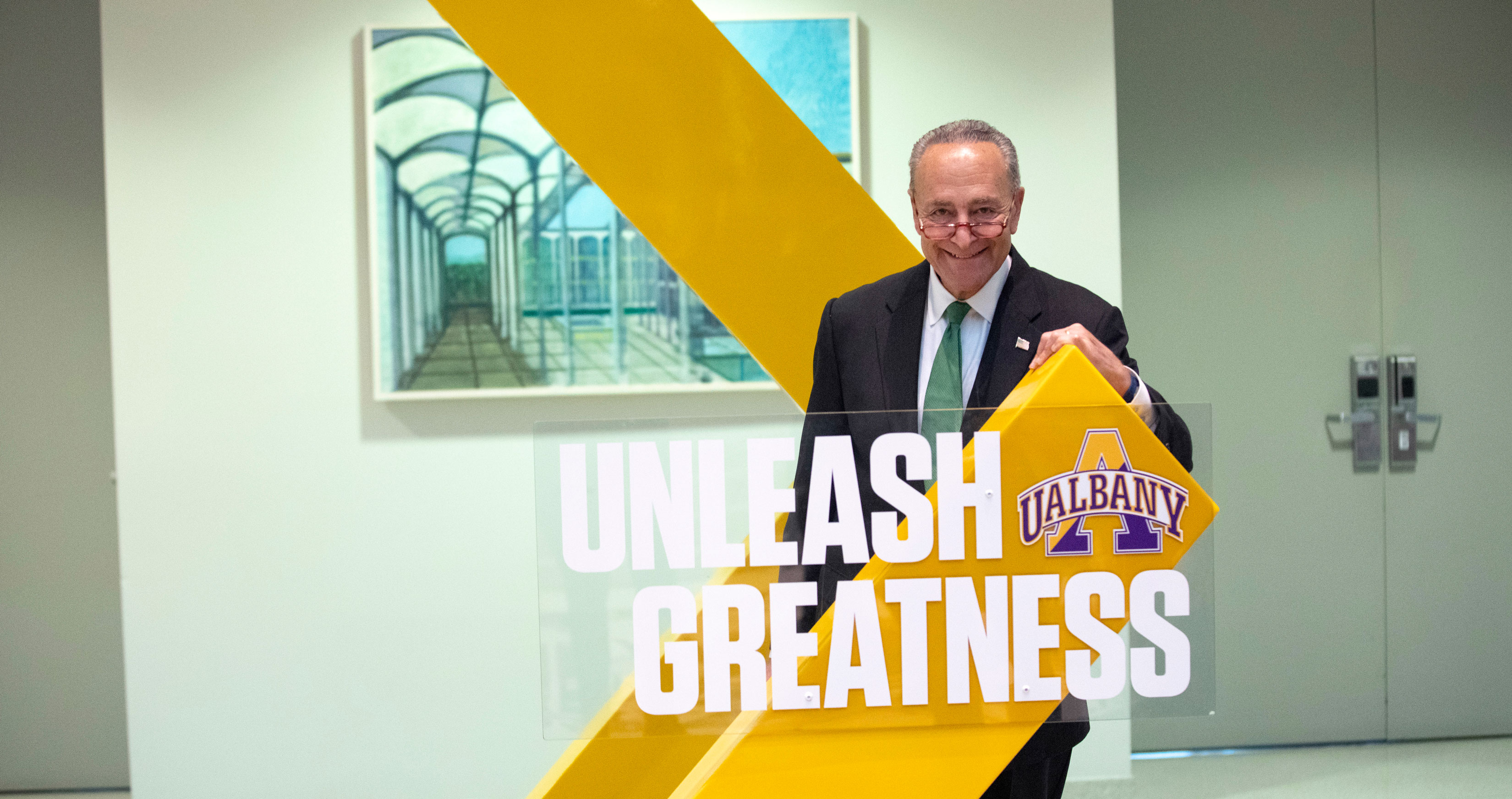 U.S. Senator Charles E. Schumer poses with an Unleash Greatness UAlbany sign.