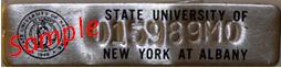 A sample of a New York State asset tag. This tag is silver metal, with the UAlbany logo, an asset code, and the words "State University of New York at Albany."