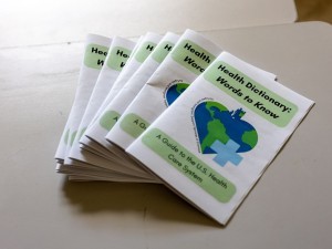 Stack of paper brochures containing health care vocabulary terms titled “Health Dictionary: Words to Know”.