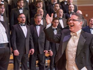 Members of Albany Pro Musica perform, a conductor in the foreground.