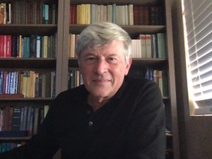 Mihai Putinar sitting with shelves of books behind him.
