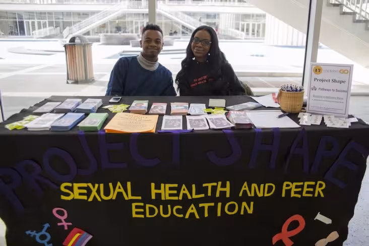 Two students at a table with information flyers on it.
