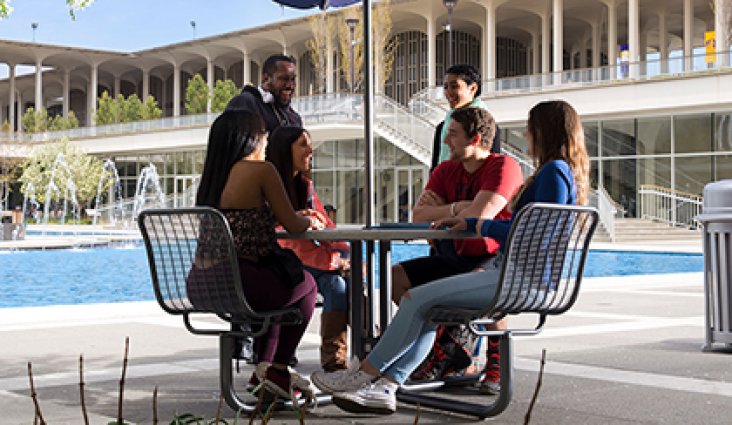 Students sitting together at a table near the main fountain.