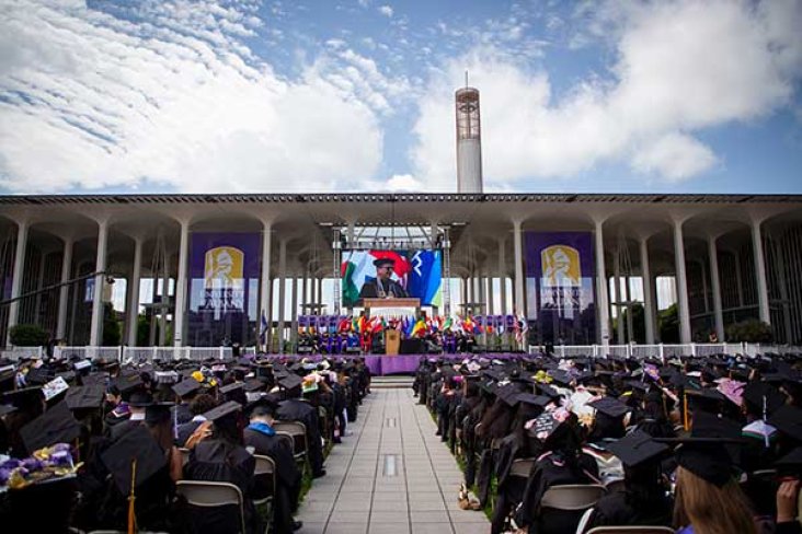 Students at Commencement listening to the University President at the podium.