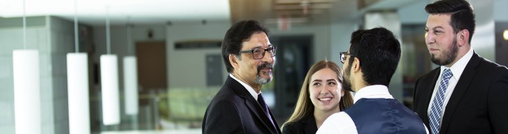 Business Administration students speaking with a professor.