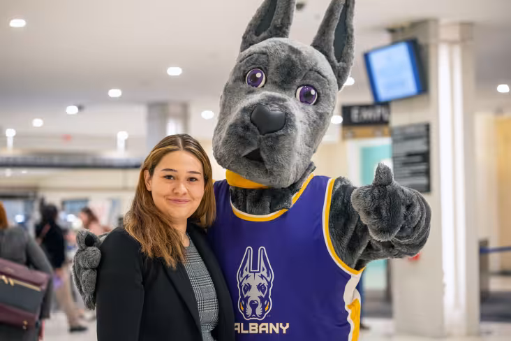 A student with UAlbany's mascot, Damien the Great Dane.