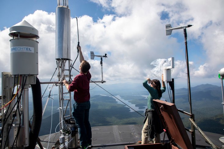 Two researchers work on outdoor equipment at the Whiteface Mountain Field Station.