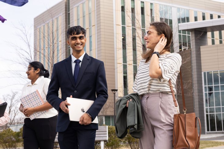 Three graduate students smile and talk while they walk away from UAlbany's ETEC building.