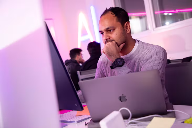 man staring at computer with a lap top in front of him