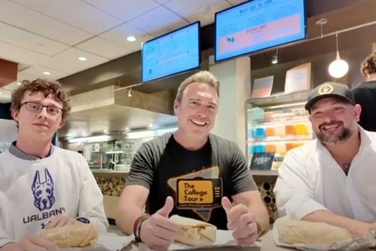 The owner of Niko's Cafe, the host of The College Tour and a UAlbany student eating together in the campus center.