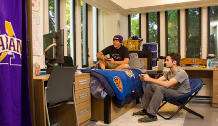 Two students playing video games in a dorm room.