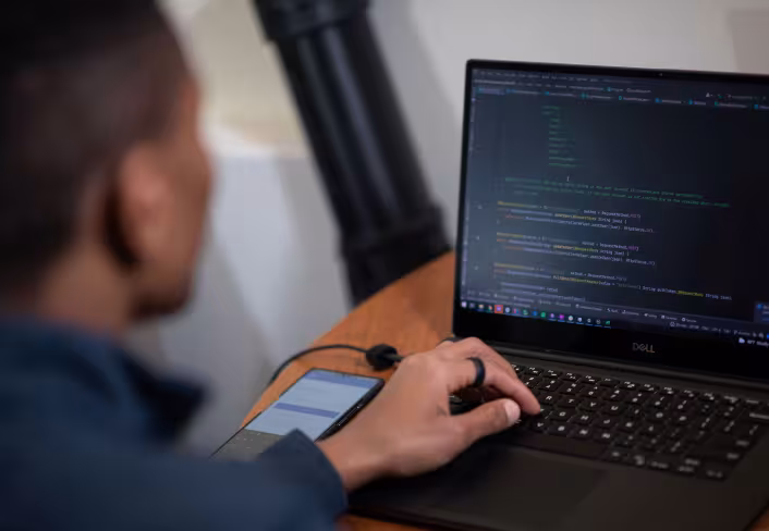 A student types computer code on a laptop.
