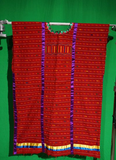 A woman's red fabric huipil with purple, yellow and blue silk ribbons.