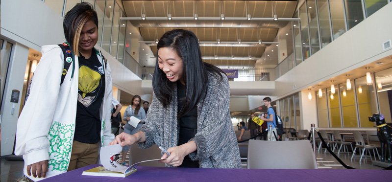 UAlbany Alum Awkwafina signing a book for a student