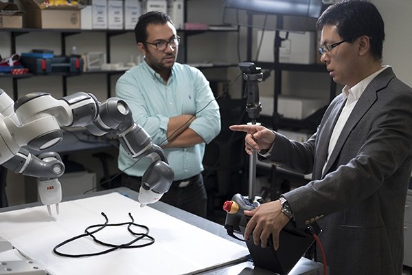 Electrical and Computer Engineering Prof. Weifu Wang and research assistant working with knot-tying robot