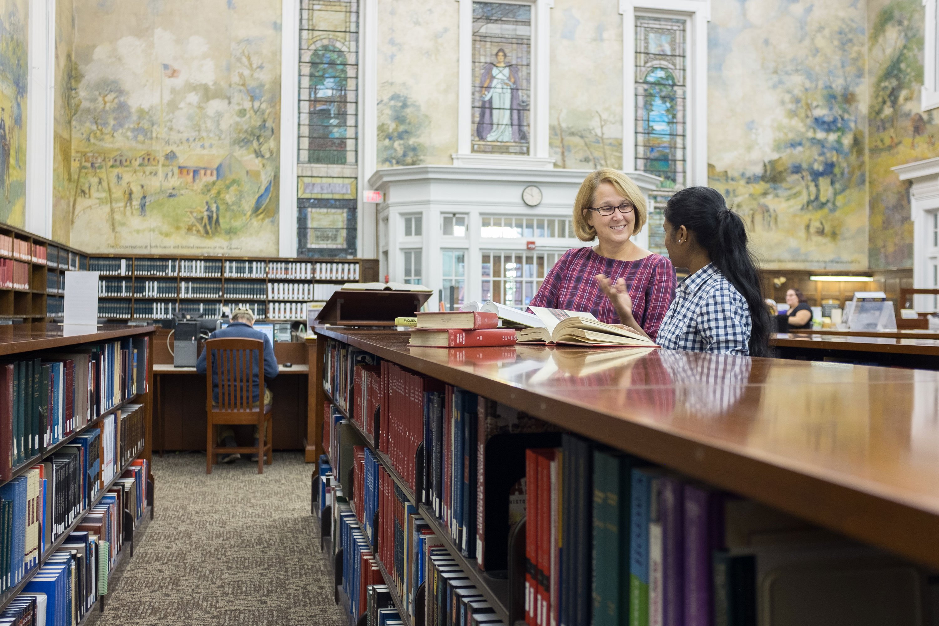 A student consults a staff member inside the Dewey Graduate Library on the Downtown Campus. 