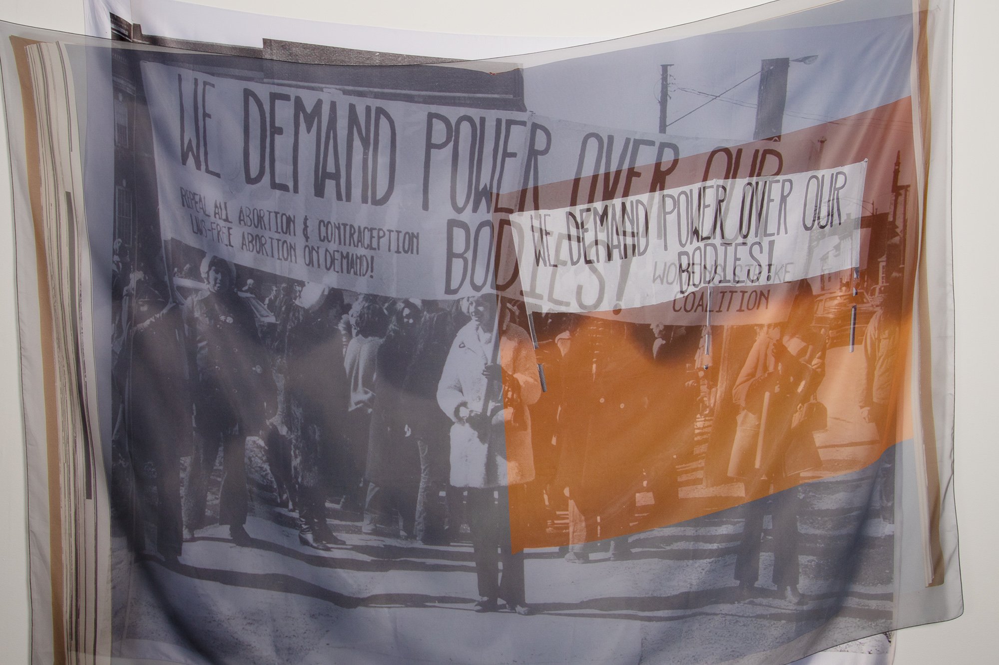 A silk banner that reads We Demand Power Over Our Bodies