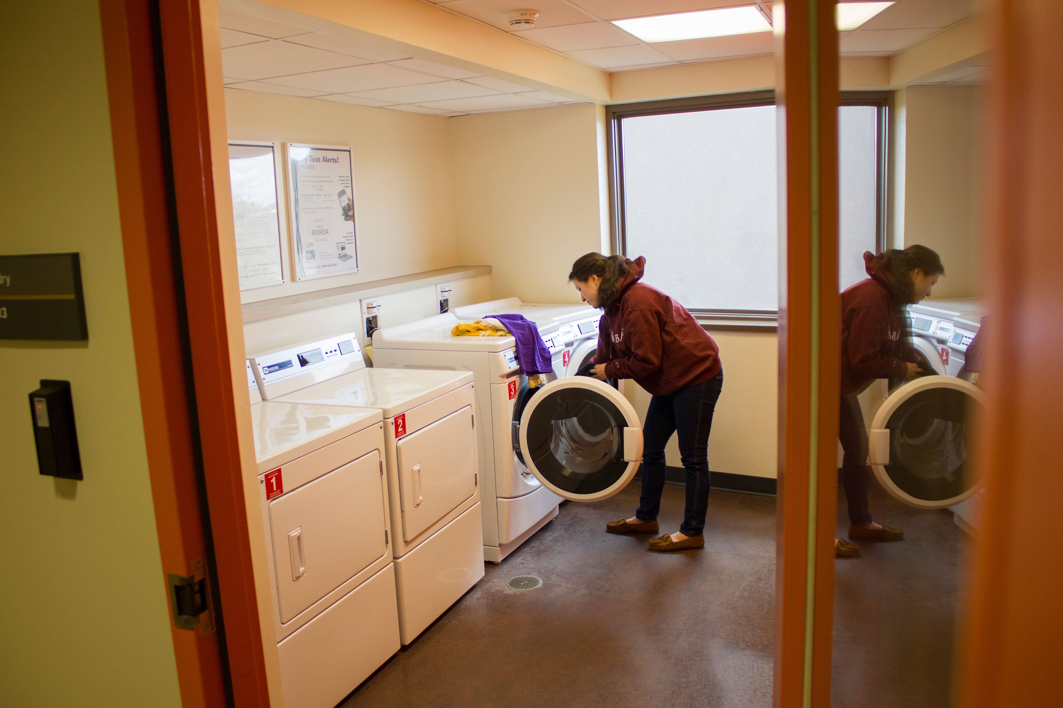 A student pulls laundry out of a machine in a Liberty Terrace laundry room