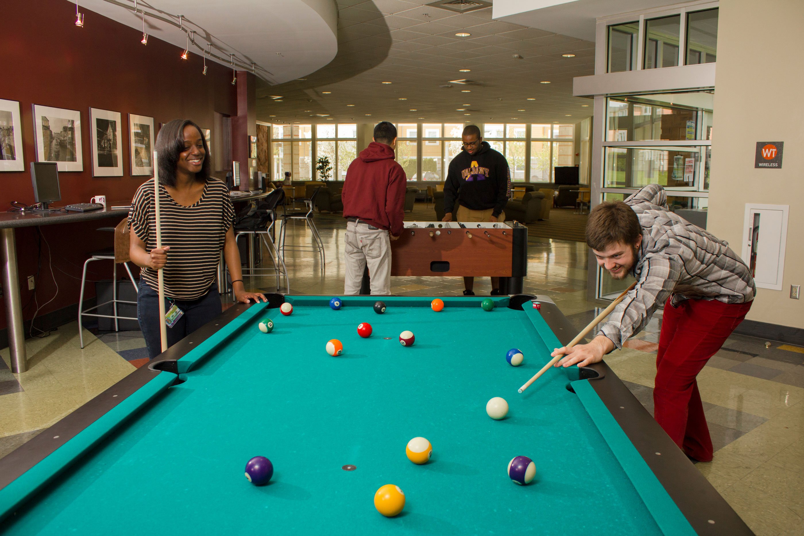 Students play billiards and foosball inside an Empire Commons lounge