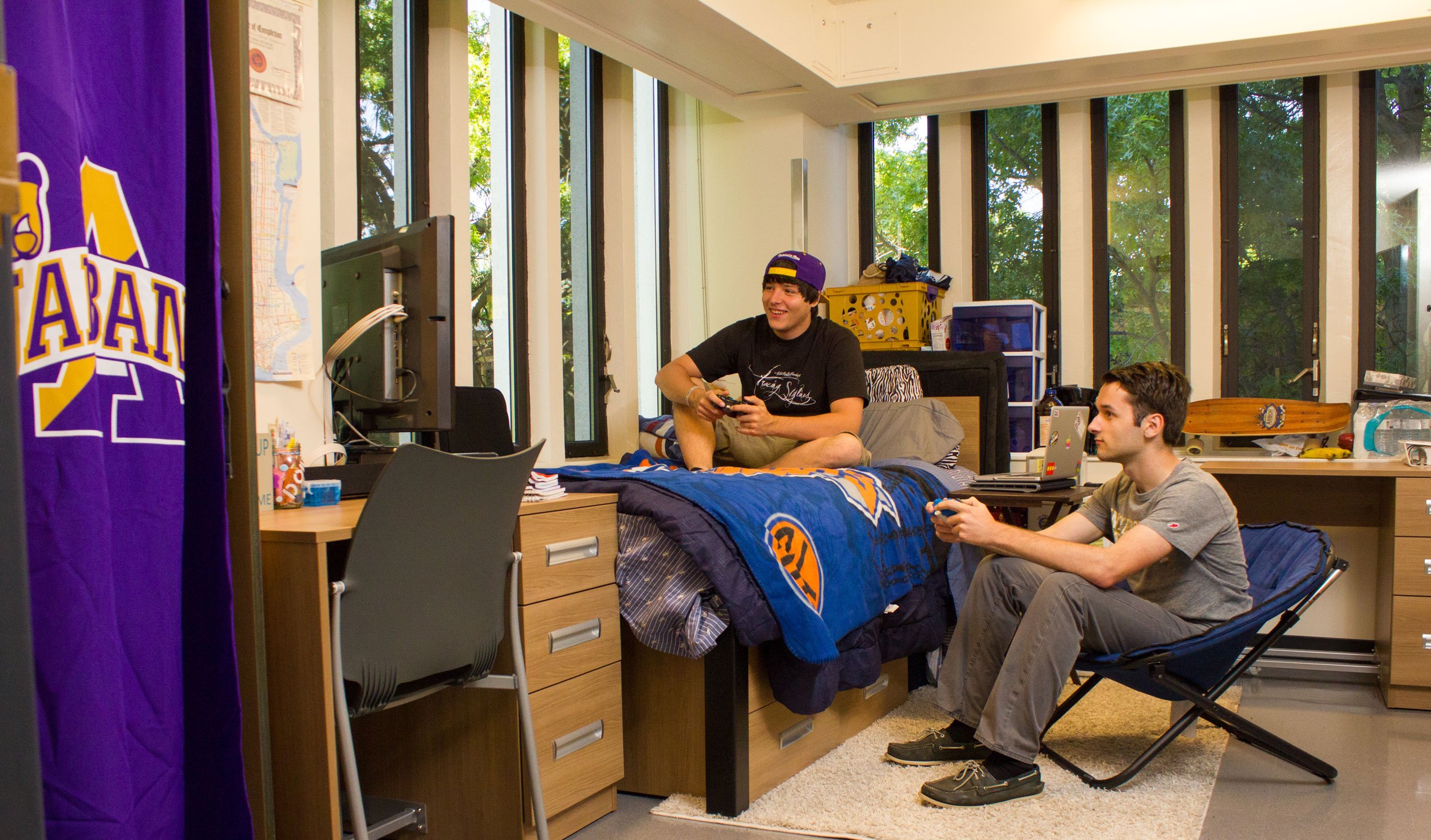 Two students play video games inside a double bedroom in Indigenous Quad