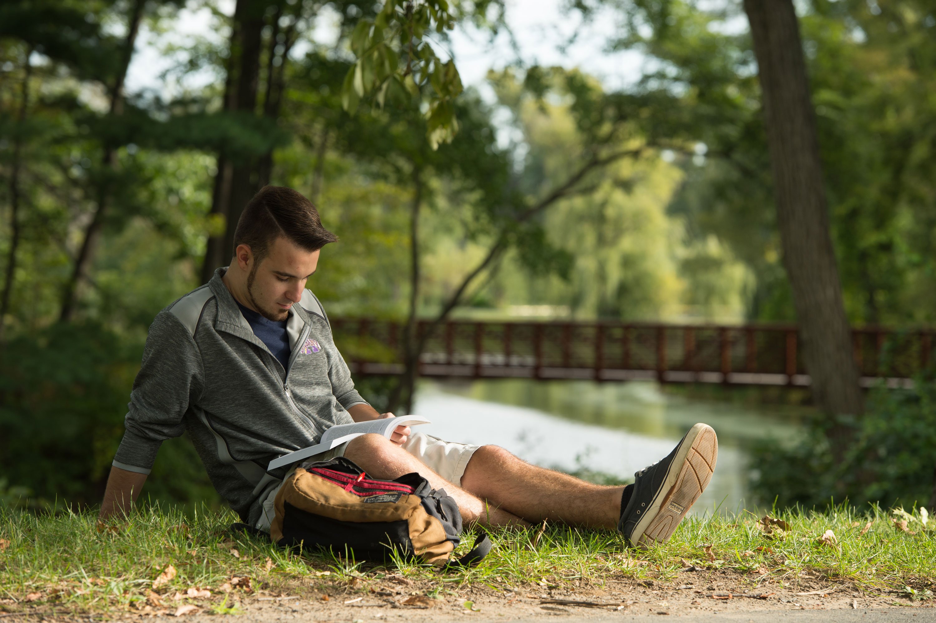 A student studies next to Parker Pond, located adjacent to Liberty Terrace