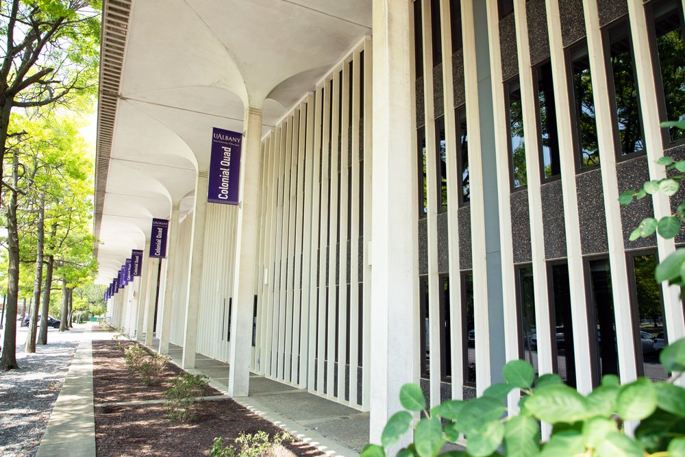 Row of purple Colonial Quad banners along the exterior of a residence hall