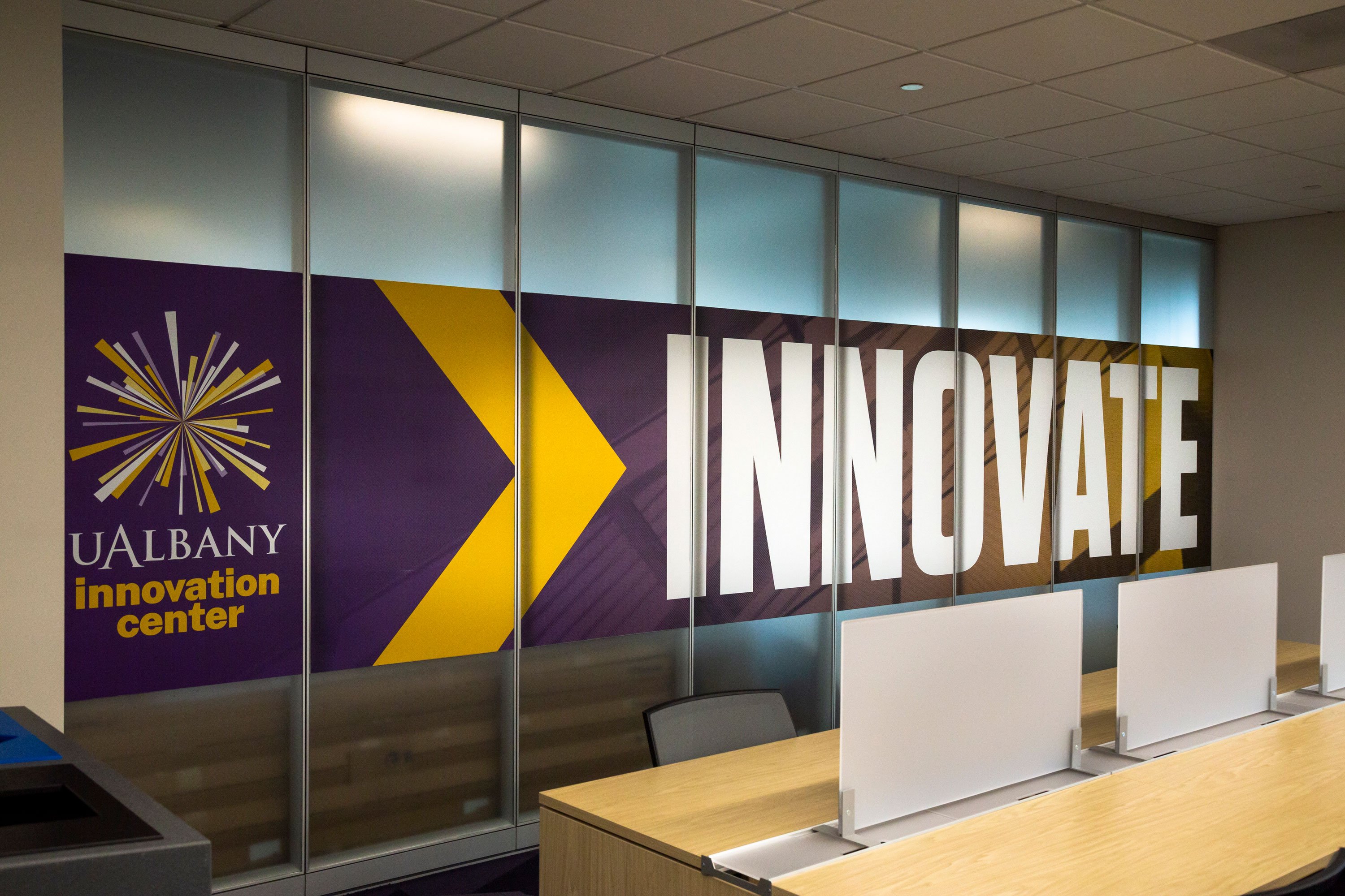 A sign inside the UAlbany Innovation Center shows the center's name and starburst logo, with the word Innovate.