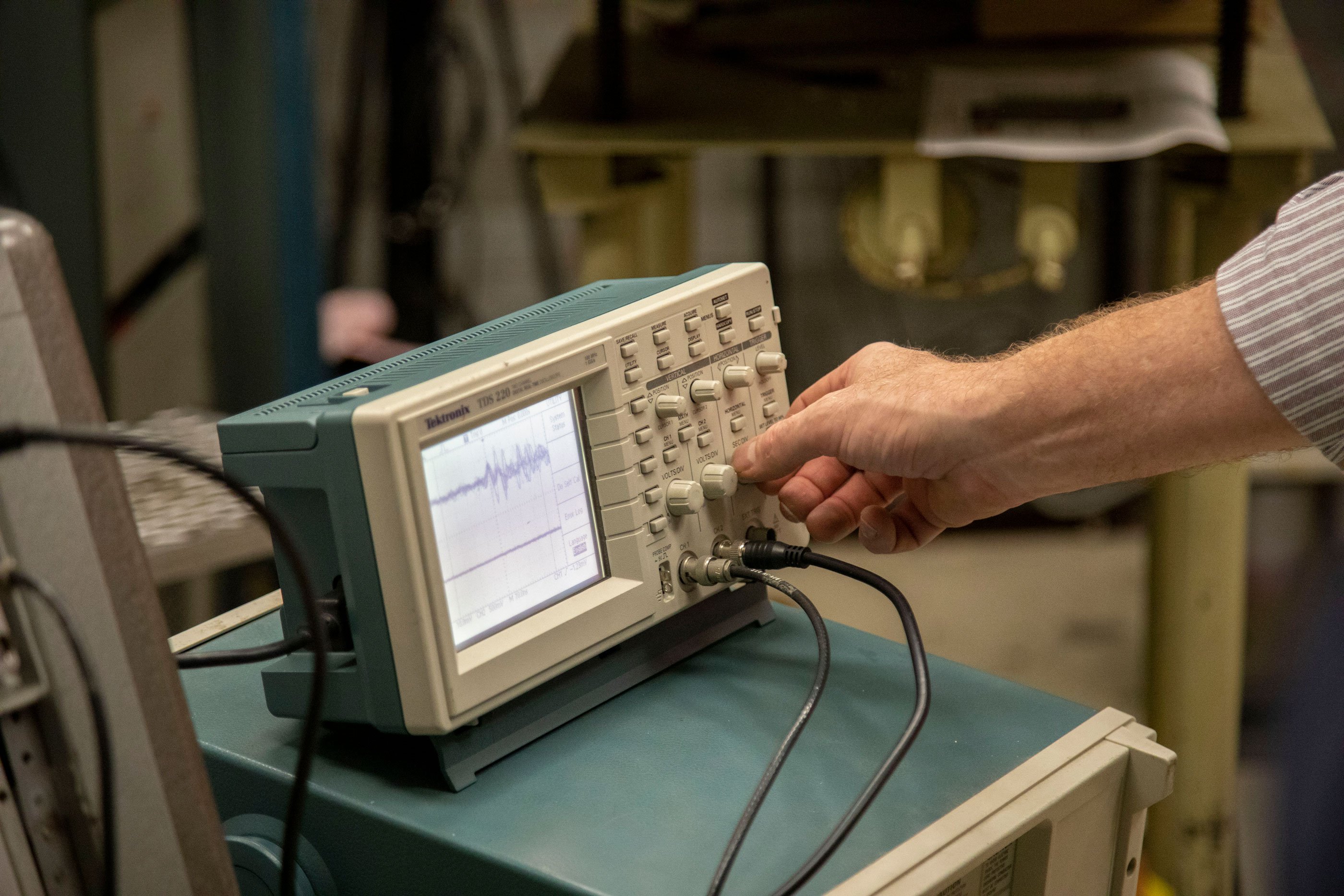 A hand turns a dial on a piece of equipment inside the Ion Beam Lab.