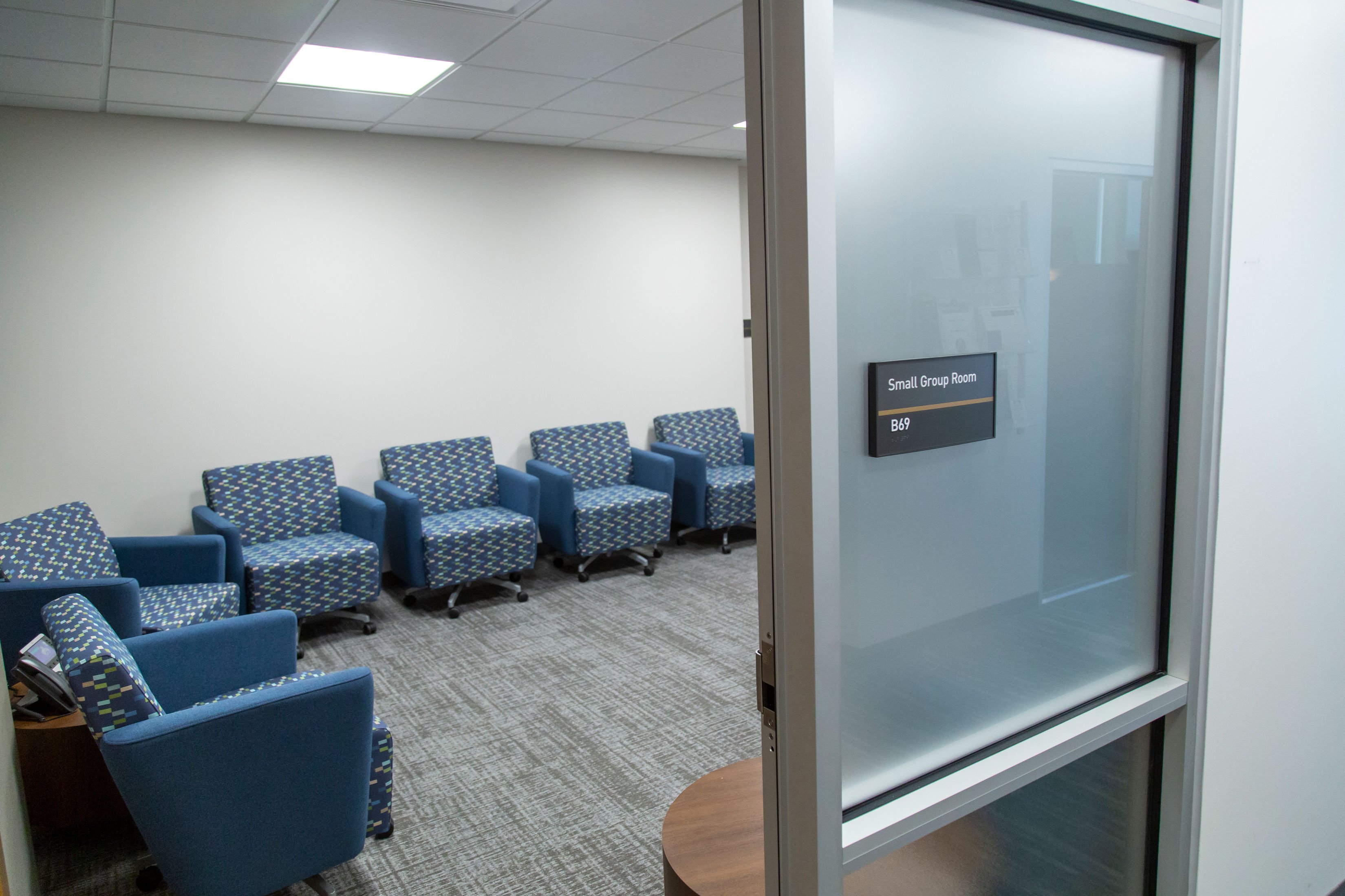 Looking into the Small Group Room through the doorway, with the room name visible besides the doorjamb. Inside, there are many comfortable chairs.