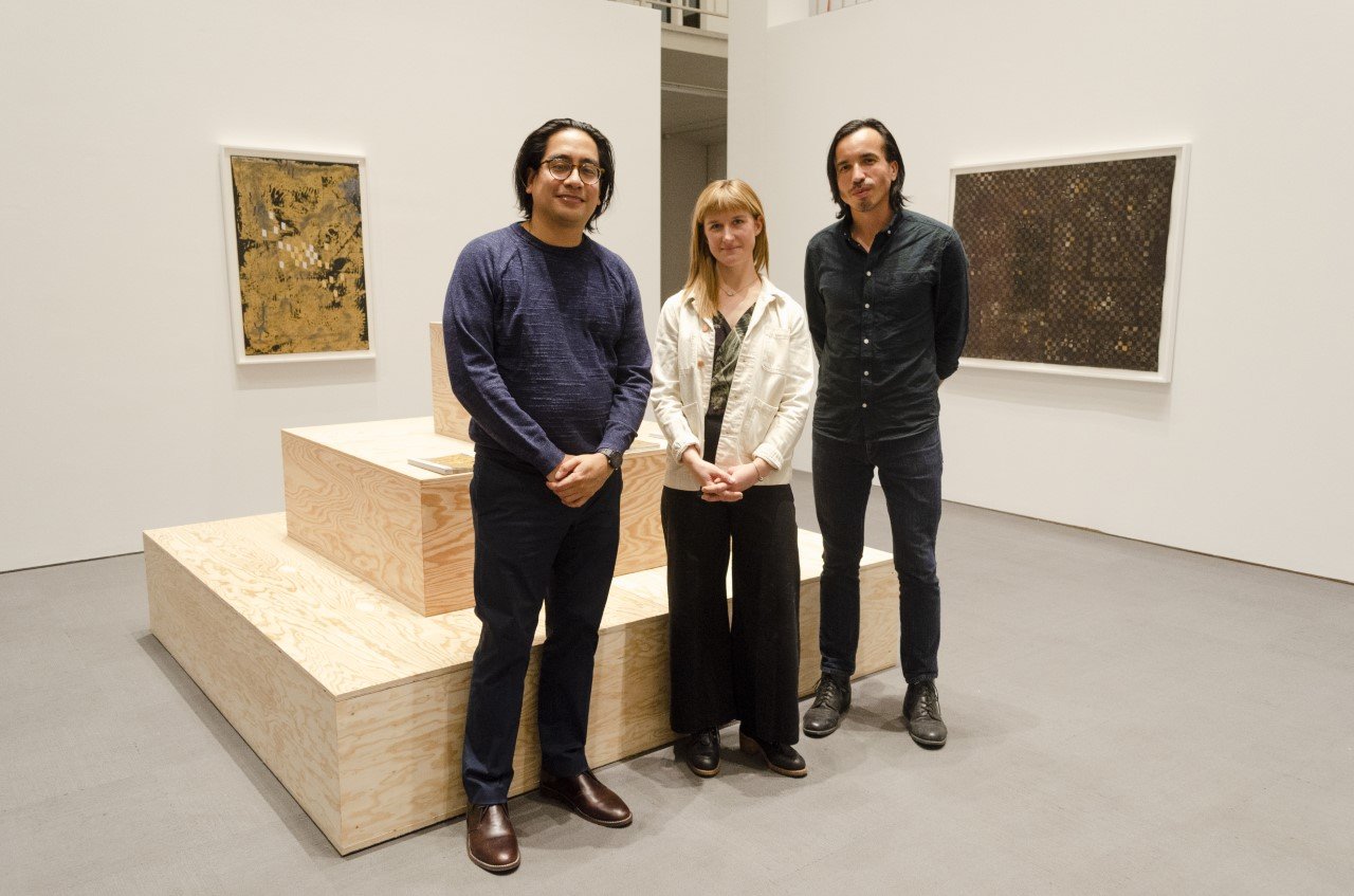 Artists standing in front of a plywood sculpture