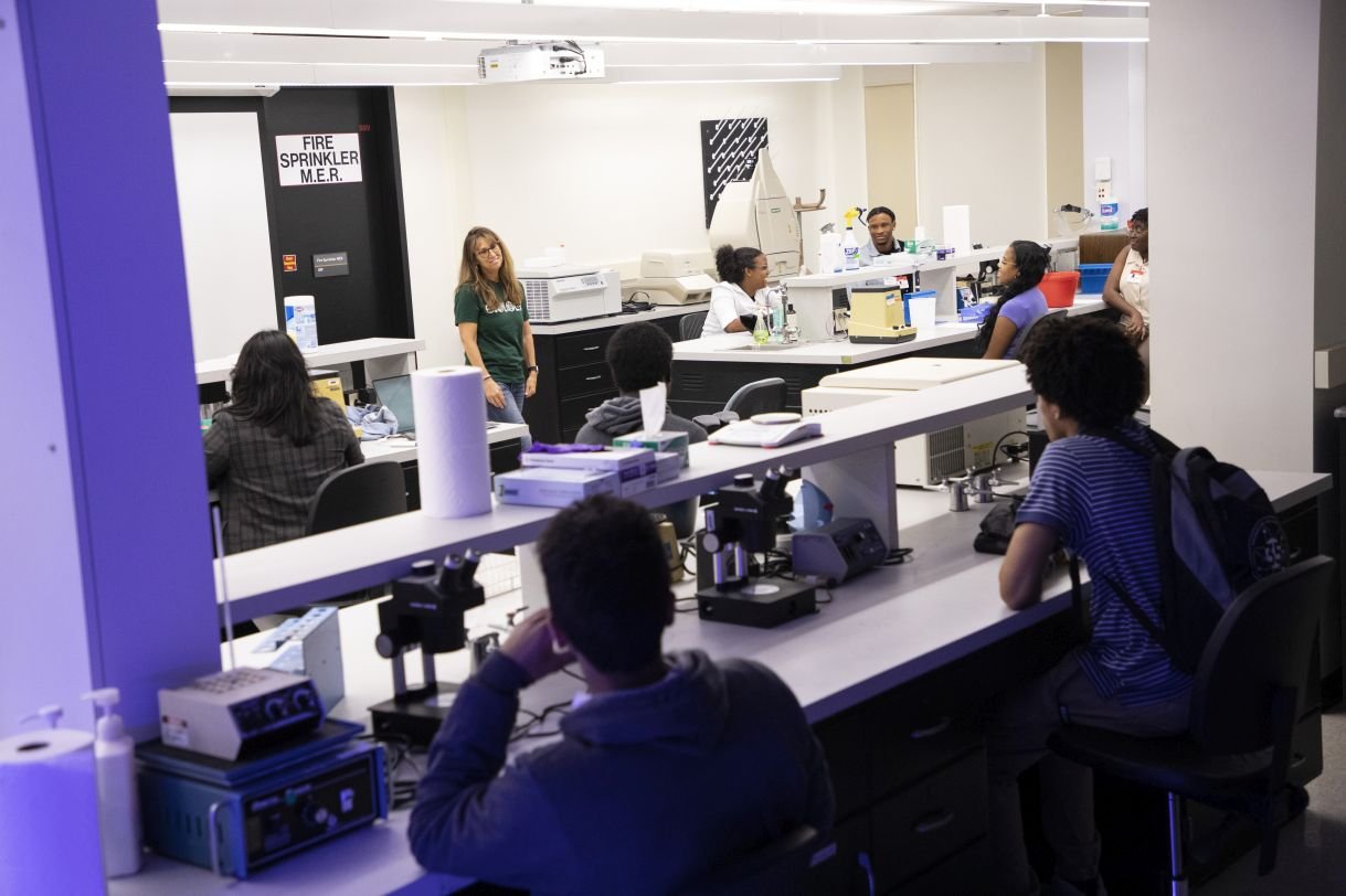 A professor addresses a lab full of students