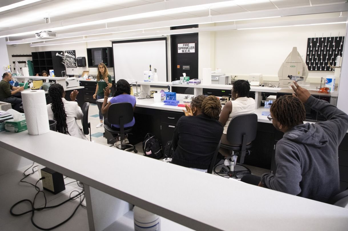 Students listen to a professor in a lab in the life sciences building