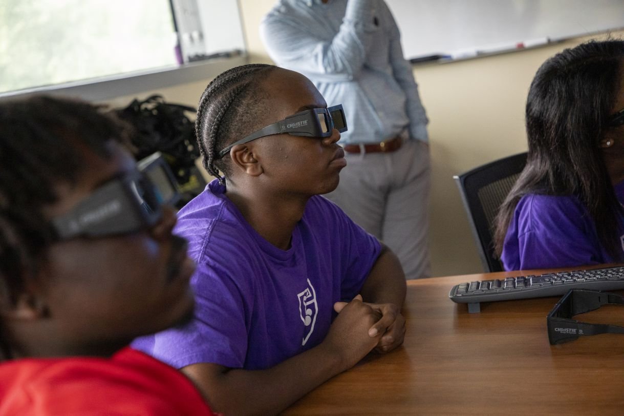 Students observe a 3D presentation wearing 3D glasses.